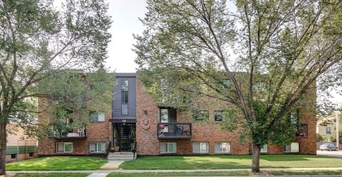 a red brick apartment building with a lawn and trees